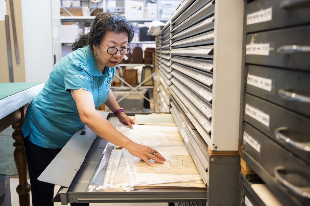 Volunteer reviewing archival maps in a drawer at the Cairns Historical Society Research Centre