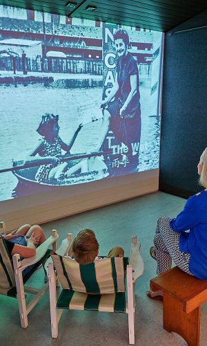 Family sitting in a projected display in the permanent exhibition space